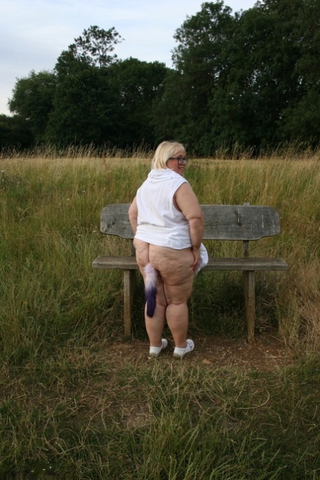 Fat British lady Lexie Cummings exposes herself on a bench in a field
