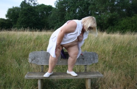 Fat British lady Lexie Cummings exposes herself on a bench in a field