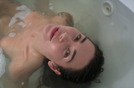 Curvy brunette Alexandra Roz fingers her shaved pussy in the bathtub