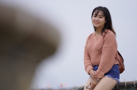 Stunning Asian babe poses in her jean shorts & sweater in public